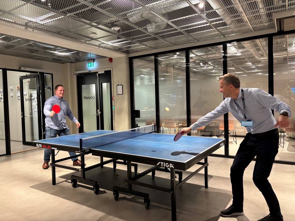 to personer spiller bordtennis i kontormiljø