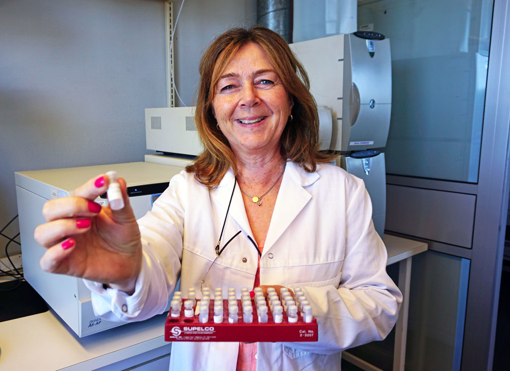 woman posing, showing a tray of small lab glasses