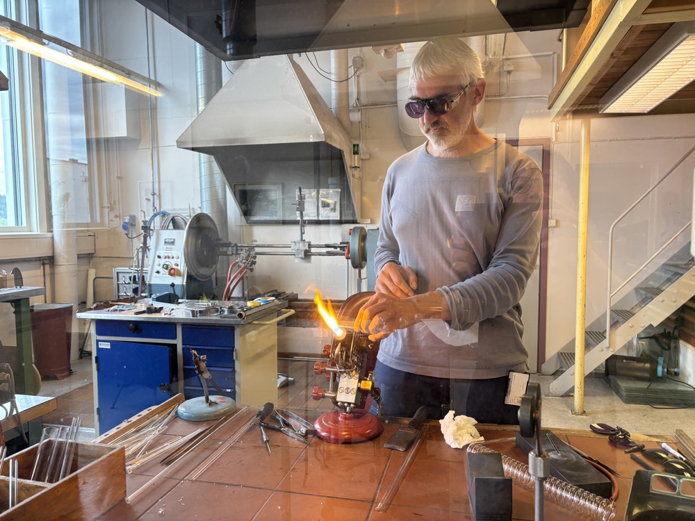 glassblower at work behind a glass screen