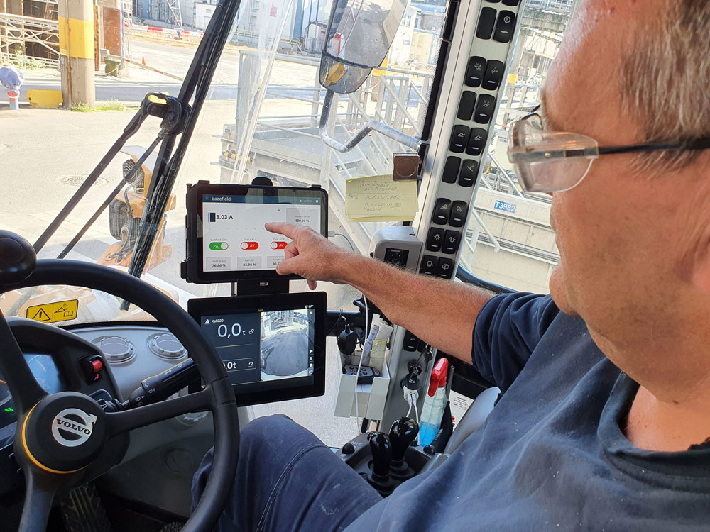 man sitting in a wheel loader and pointing at a tablet