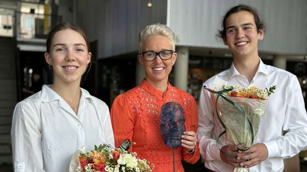 tre personer, poserer, holder i blomsterbuketter og glasskunstverk