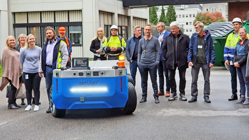 a crowd standing outdoors observing the robot on wheels