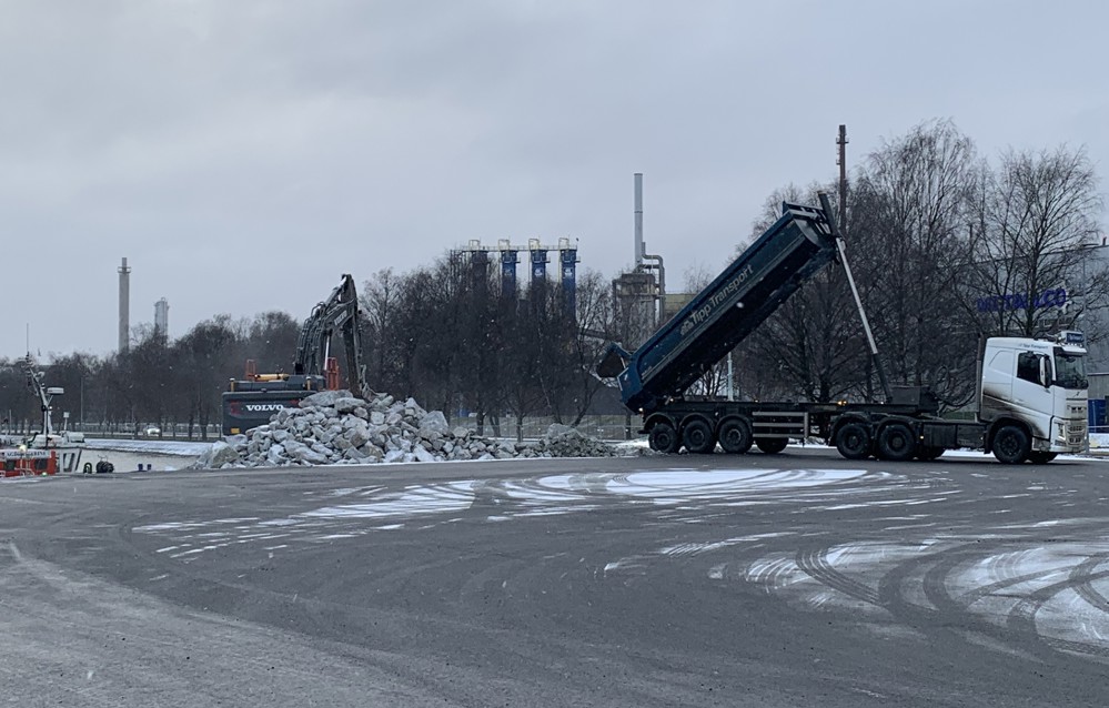 anleggsområde, bil med lasteplan tipper stein mens gravemaskin laster stein over på leker.