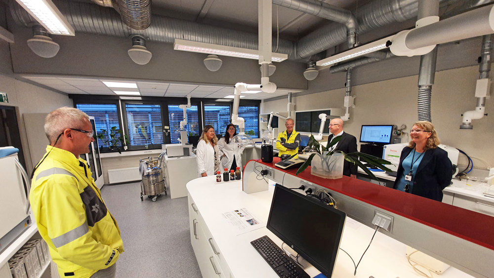 besøkende står i ny lab ved rød disk