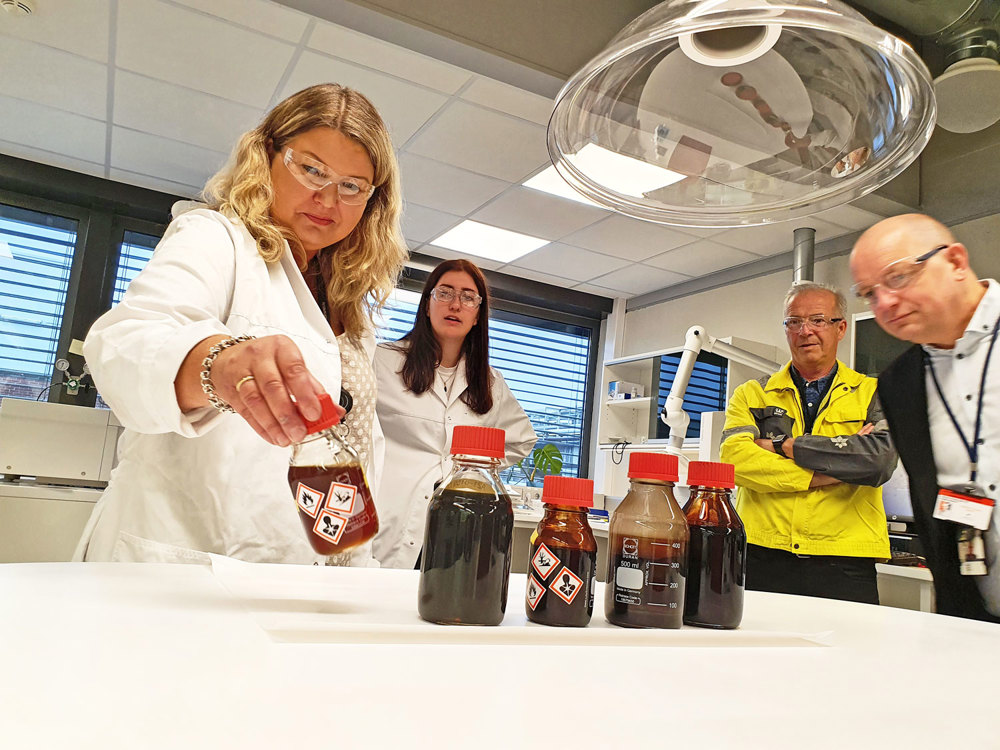 fire personer studerer oljeprøver på småflasker i lab