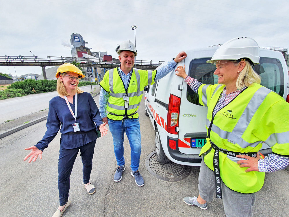 three people standing by a car, industrial, laughing