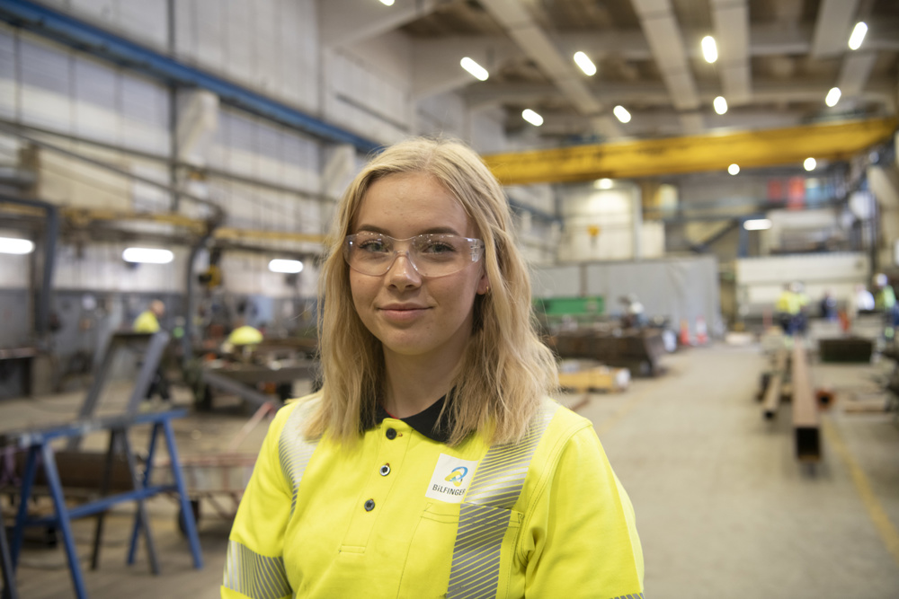young blond female apprentice in a workshop hall