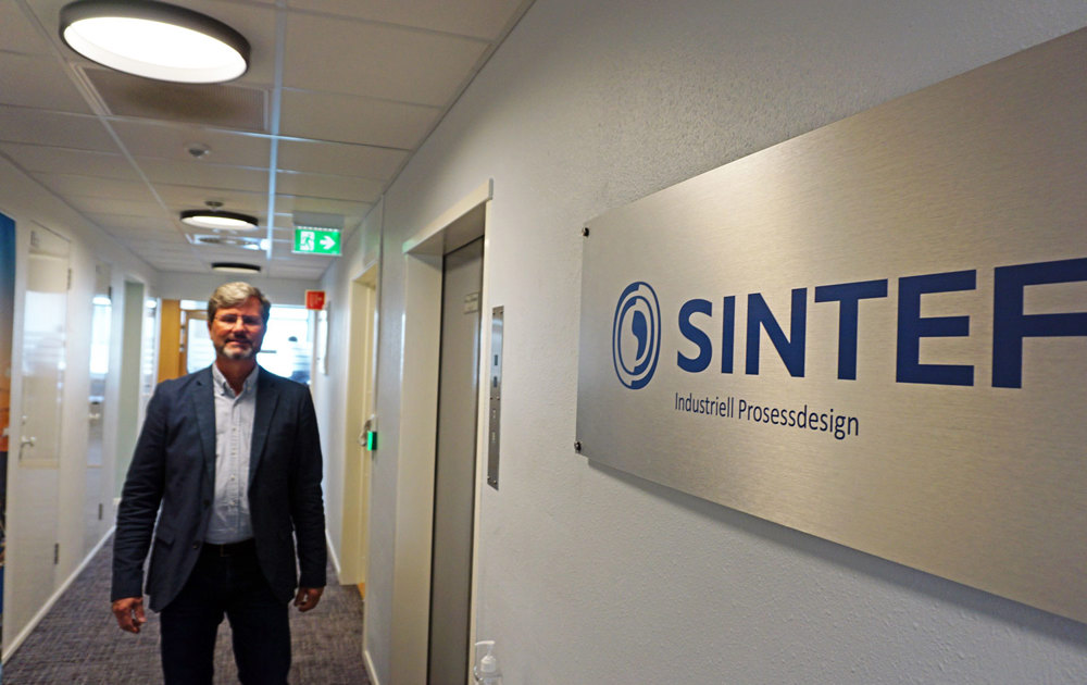 man walking in long white narrow corridor, business logo on the wall