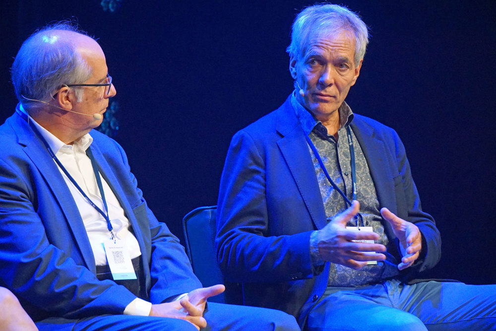 two men on stage gesticulating and talking