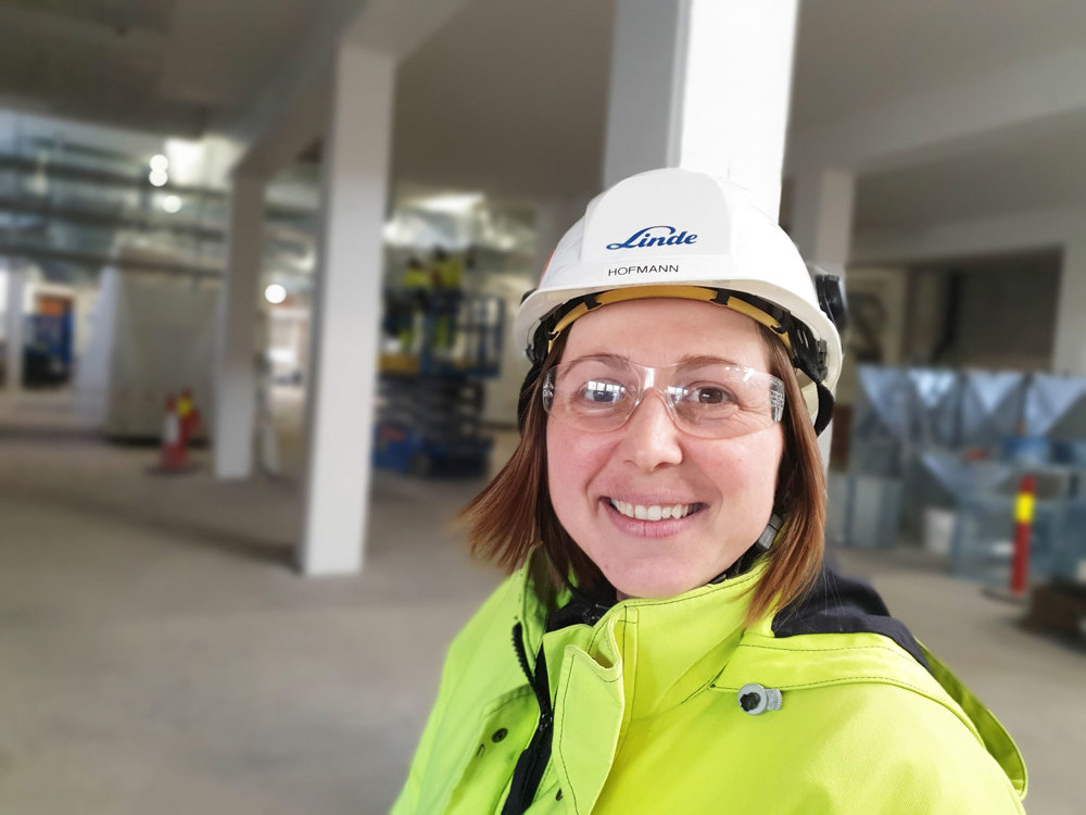 portrait of woman, white helmet, yellow jacket, industry hall