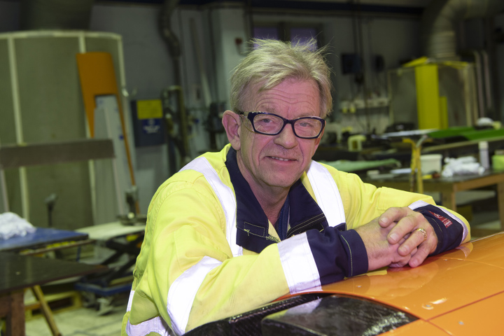 portrett av mann i gul jakke, begge armene ligger på et oransje skrog