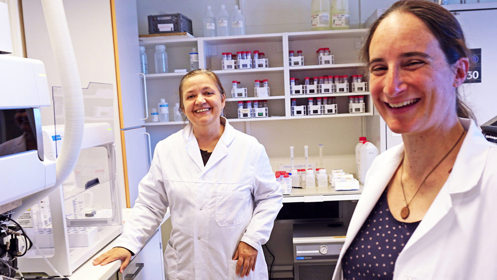 two women in lab, posing, smiling