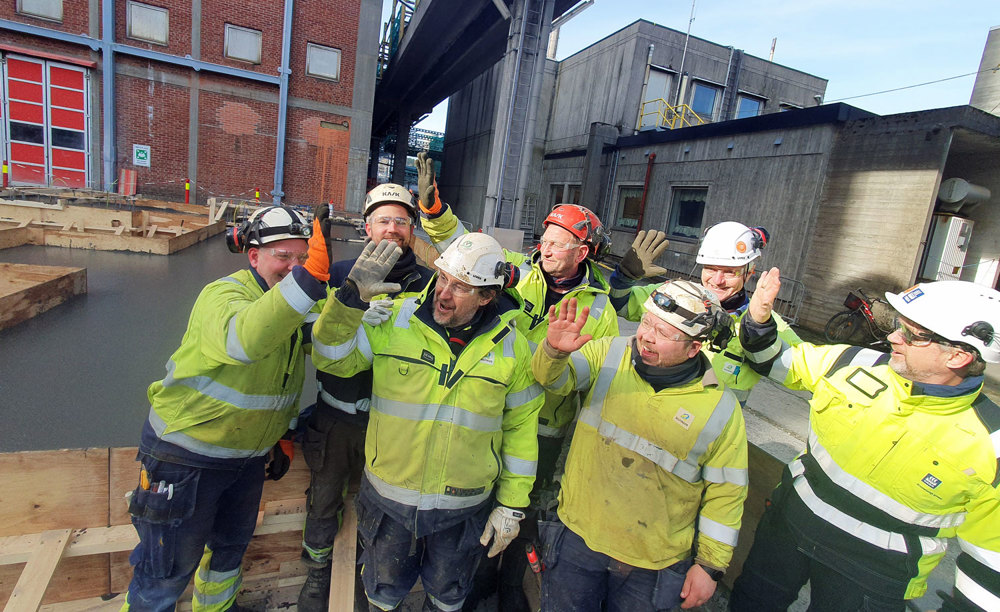 a group of seven people, high-five, outside concrete buiodings, industry