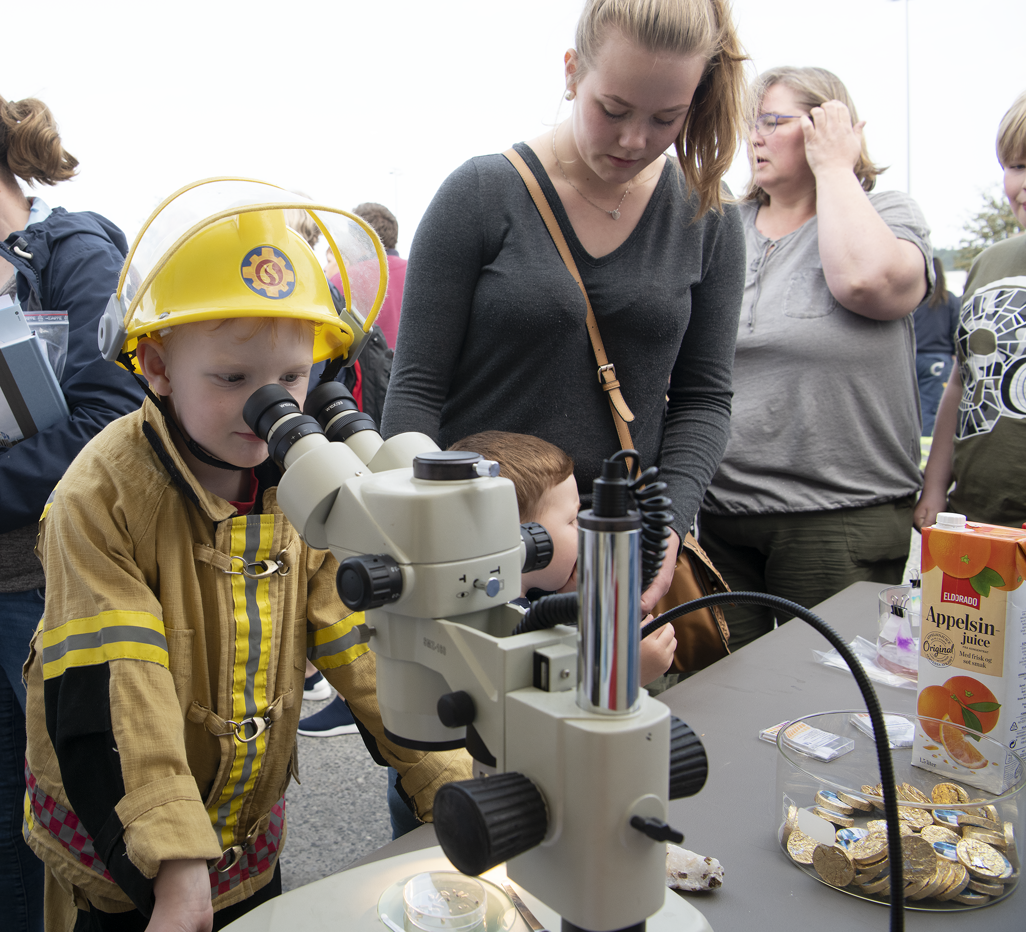 Ung gutt utkledd som brannkonstabel kikker i mikroskopet. Nabofesten, juni 2019. Foto: Ole Bjørn Ulsnæs.