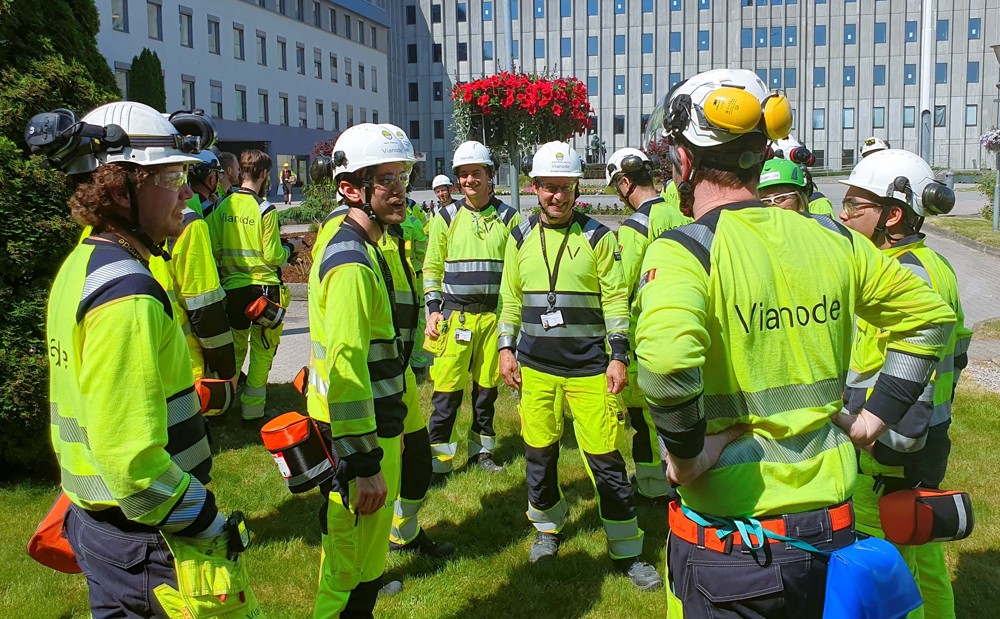 Ansatte står ute på plenen i parkområdet utenfor industriparken og samtaler med hverandre.