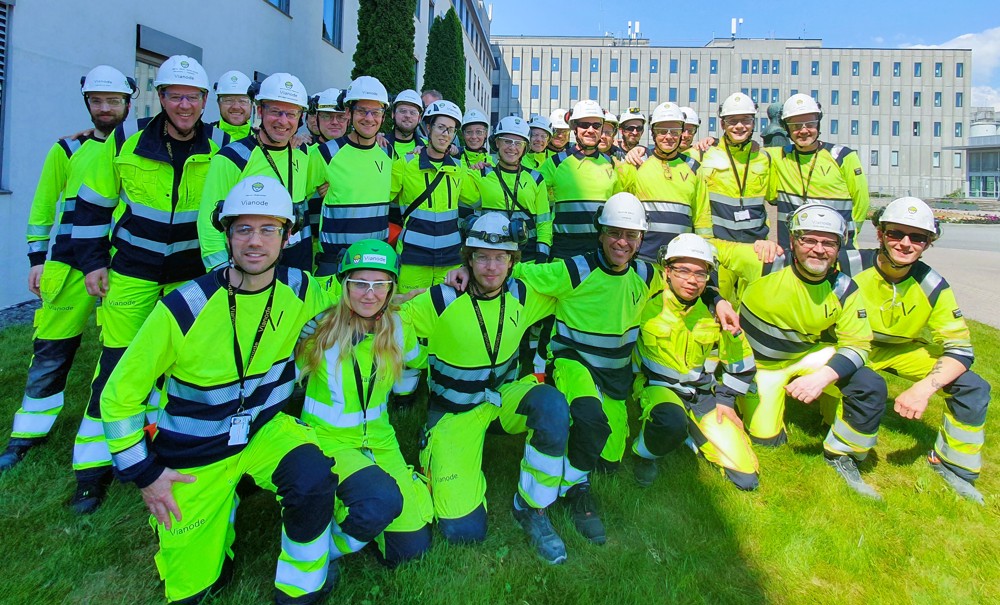 lagbilde, alle nyansatte samlet på gressplen, bakerste rad står, forreste rad sitter på kne, rundt 30 personer kledd i gult og blått, arbeidsklær og hjelm.